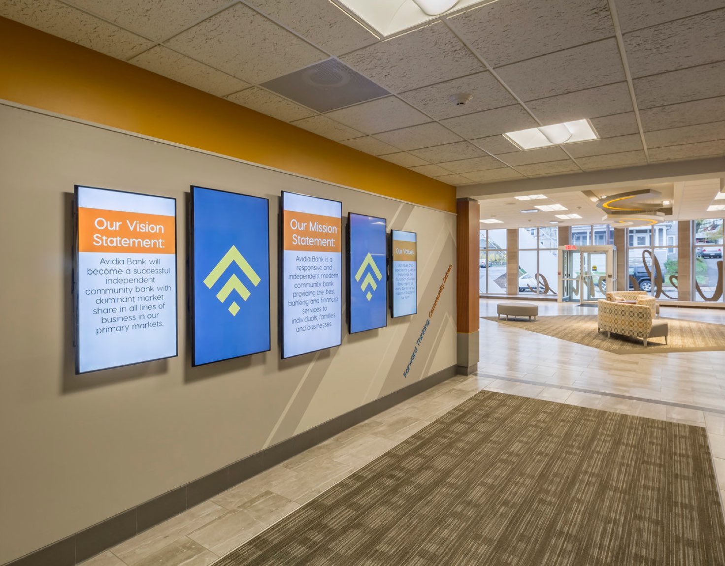 A hallway with monitors displaying a vision statement