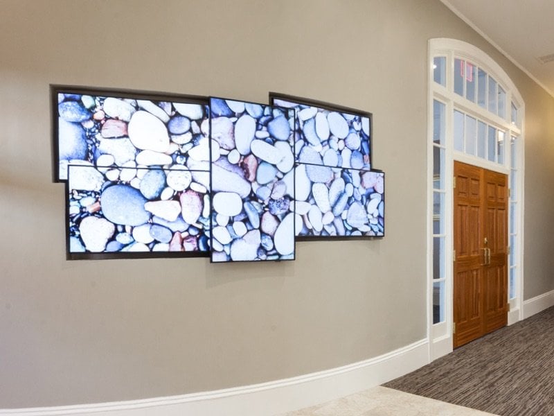 A hallway with a wall of monitors displaying pretty rocks