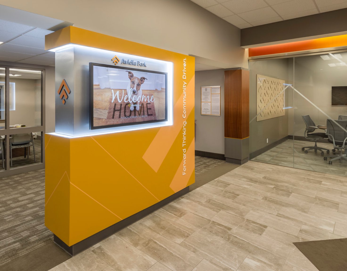 An orange wall in a lobby with a television screen built into it.