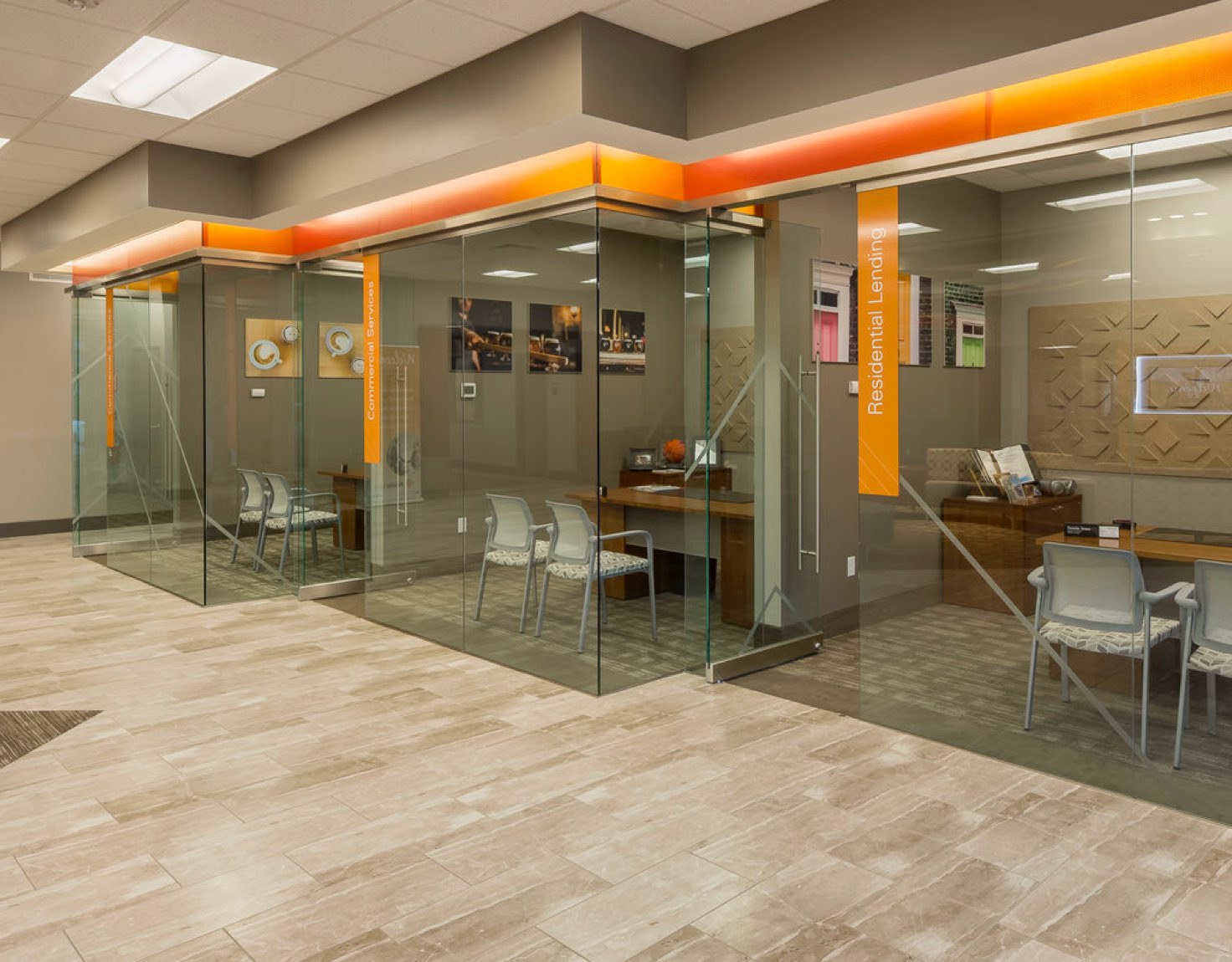 A wall of glass offices with identical desks and chairs in them.