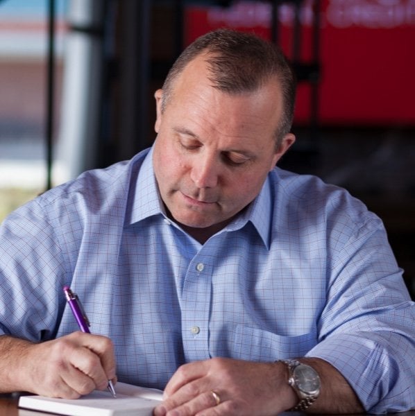 A man writing with a pen on a pad of paper.