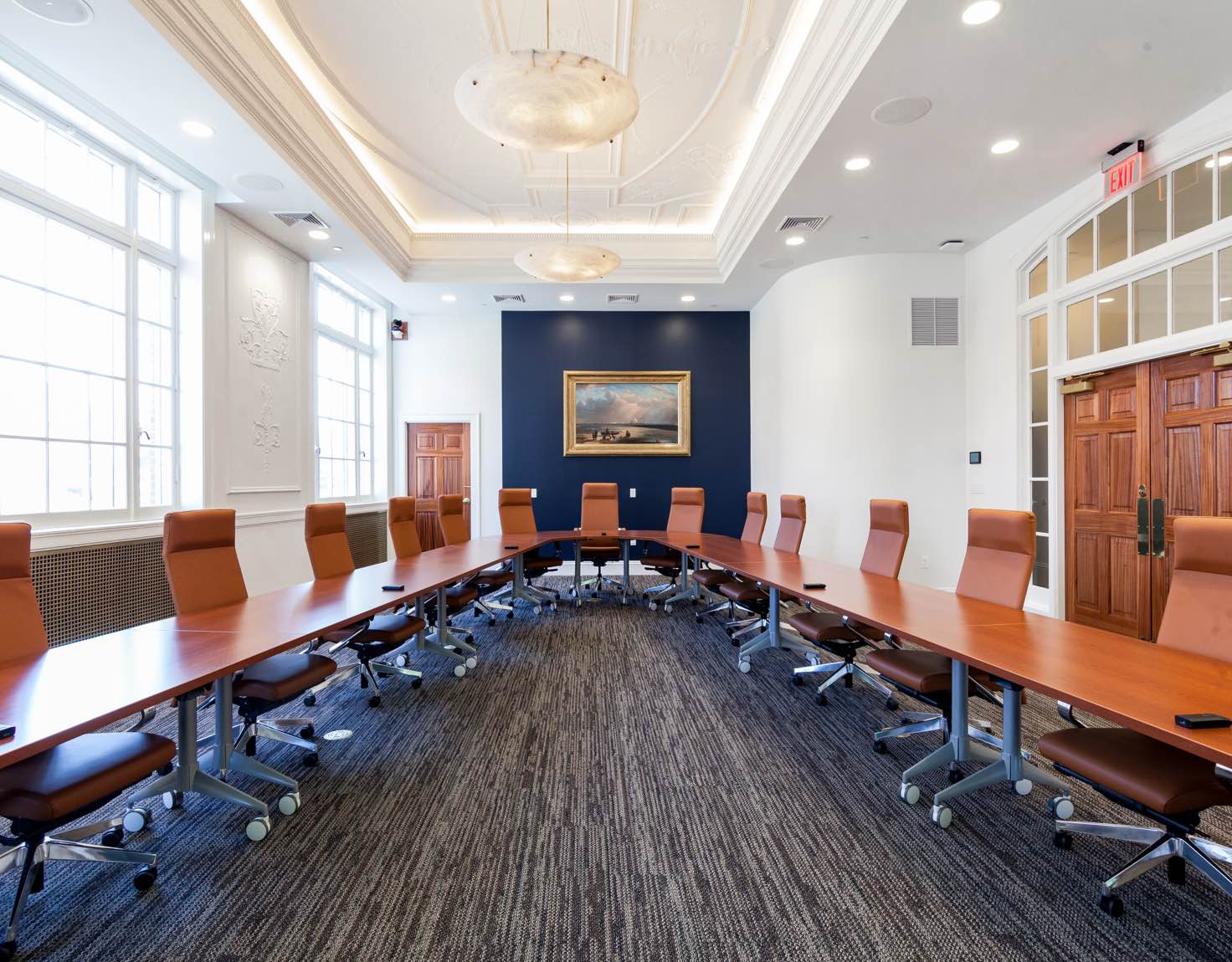 A conference room with a "V" shaped table and many brown chairs on wheels.