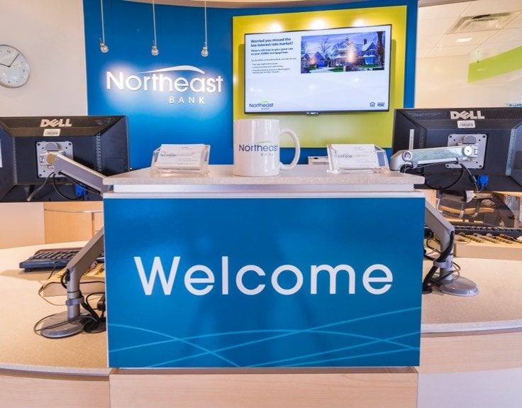 A bank teller desk with a blue Welcome sign.