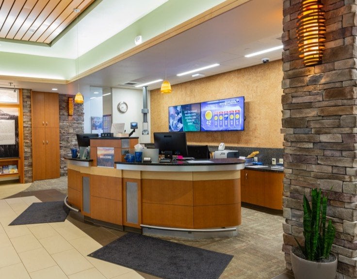 A front desk in a lobby with television screens behind it.