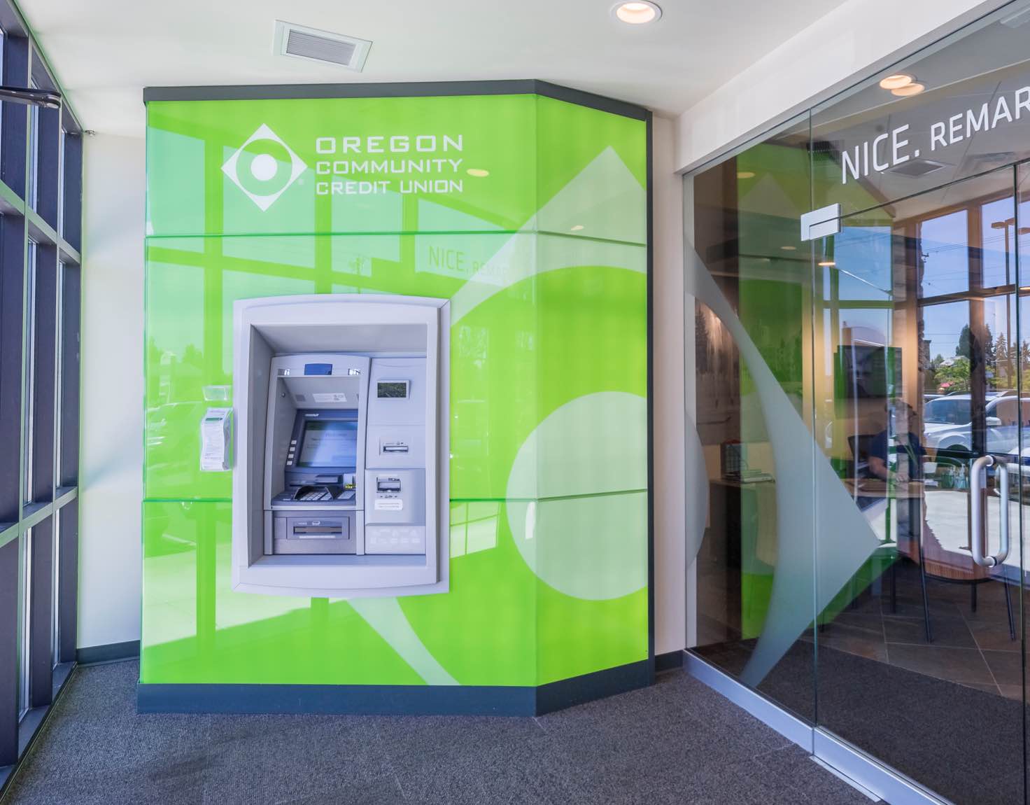A green ATM in a bank entrance way.