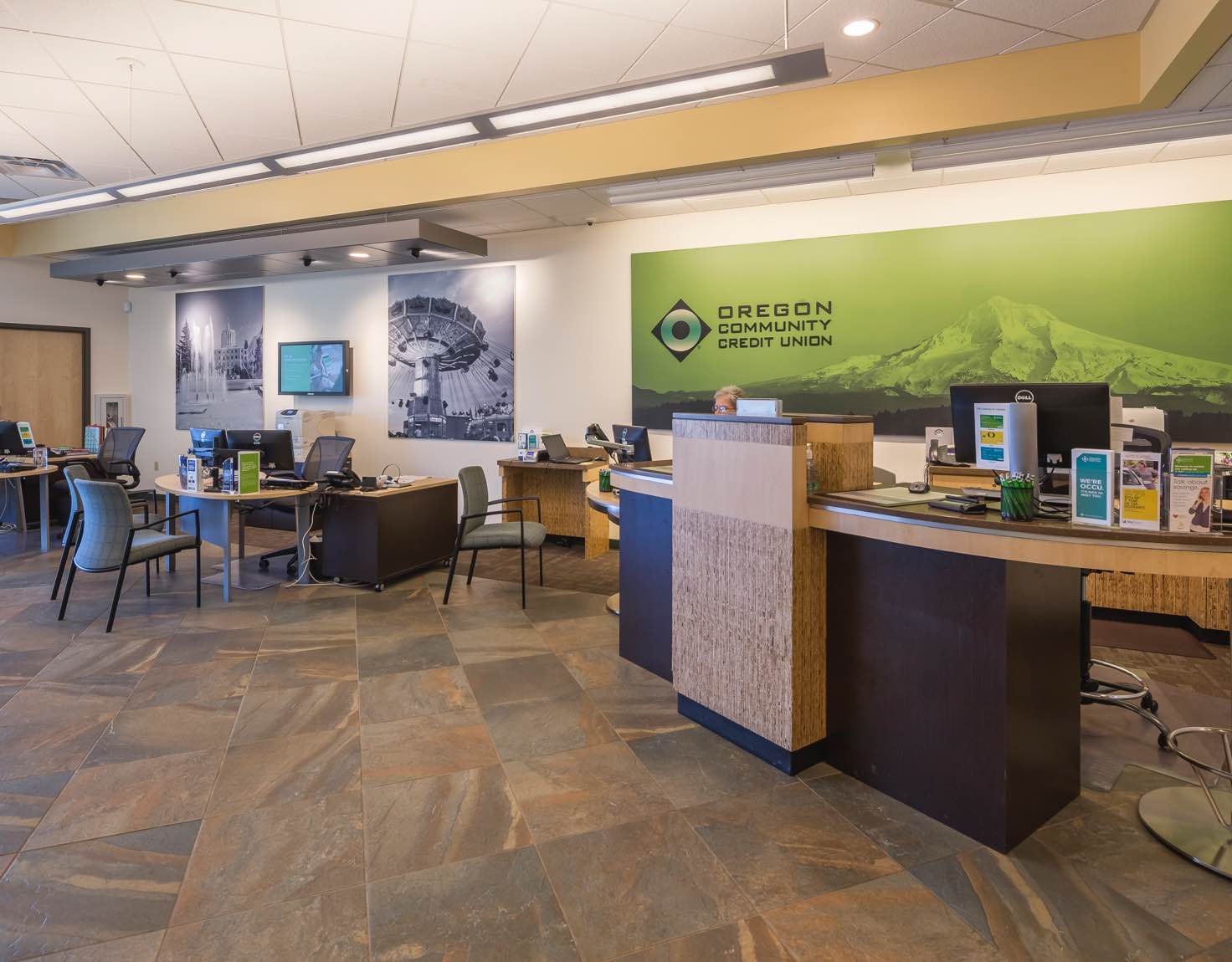 A bank lobby with brown tile floors and a green sign displaying a mountain range.