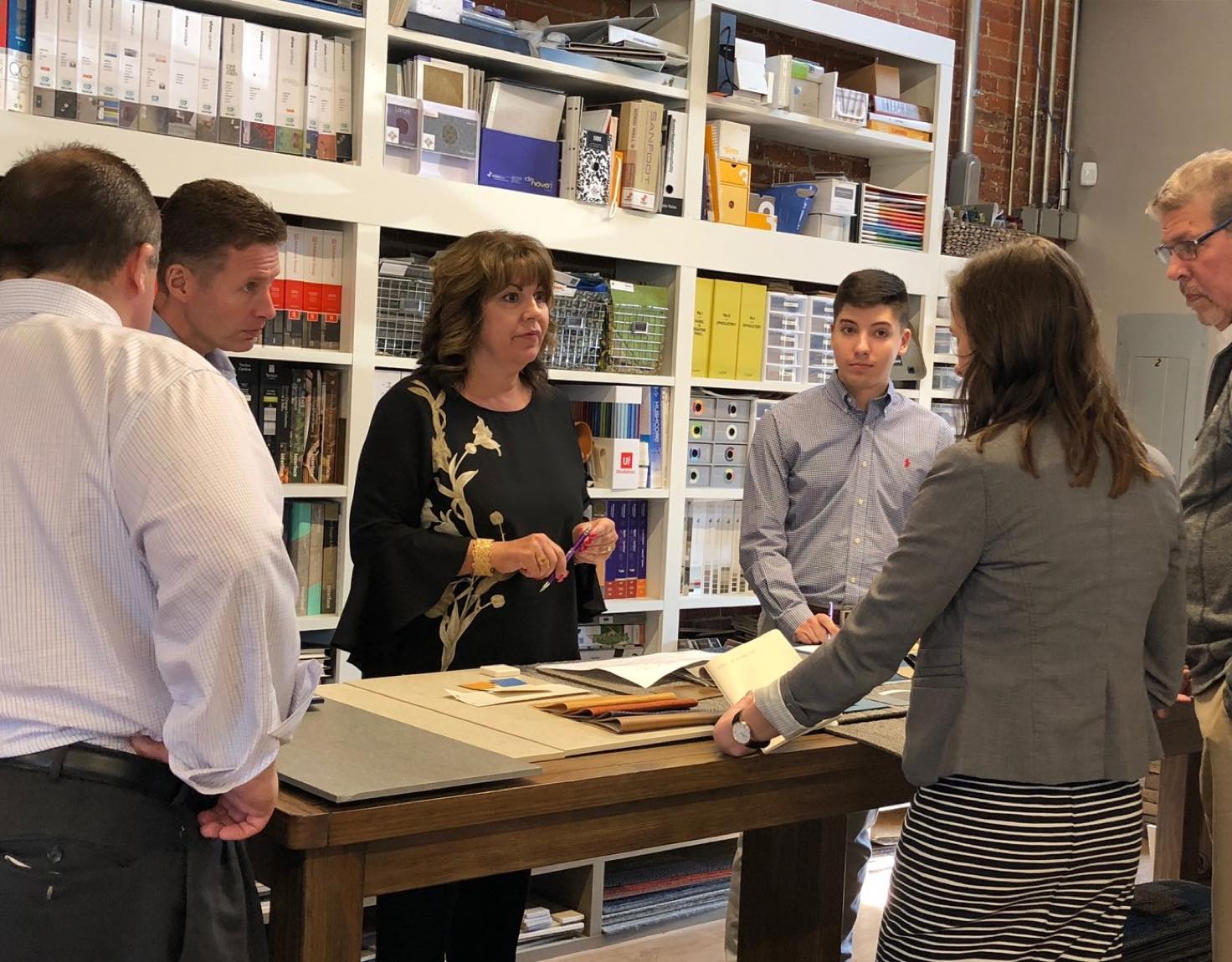 A group of coworkers standing around a table talking.