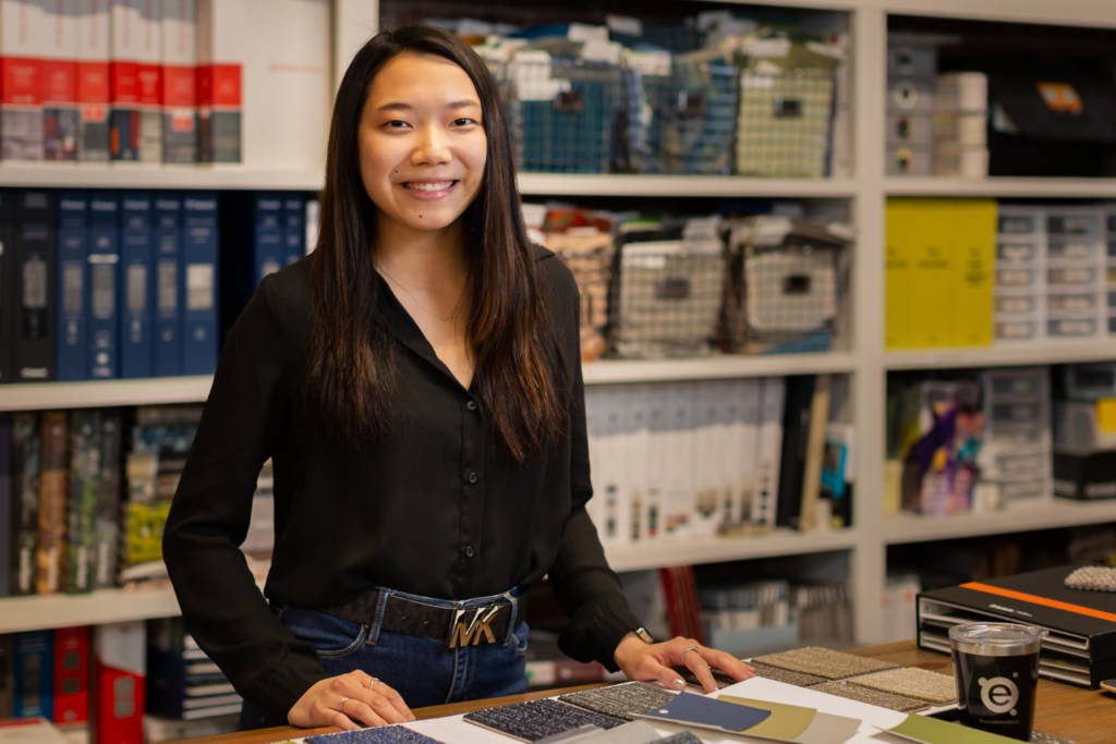 A young woman standing at a table with material samples.