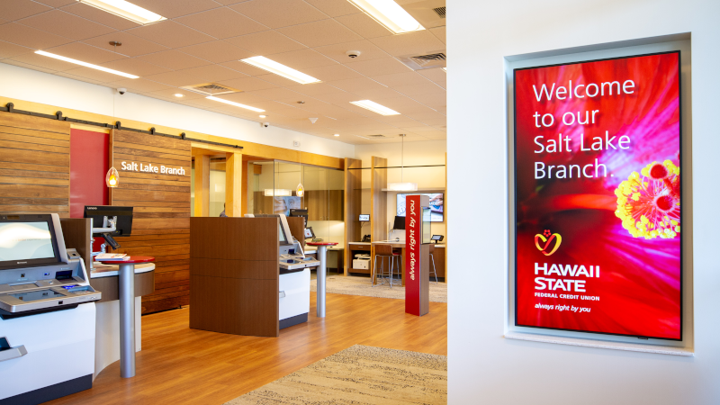 A bank lobby with self-service, teller machines, and a red "Welcome" sign on the wall.