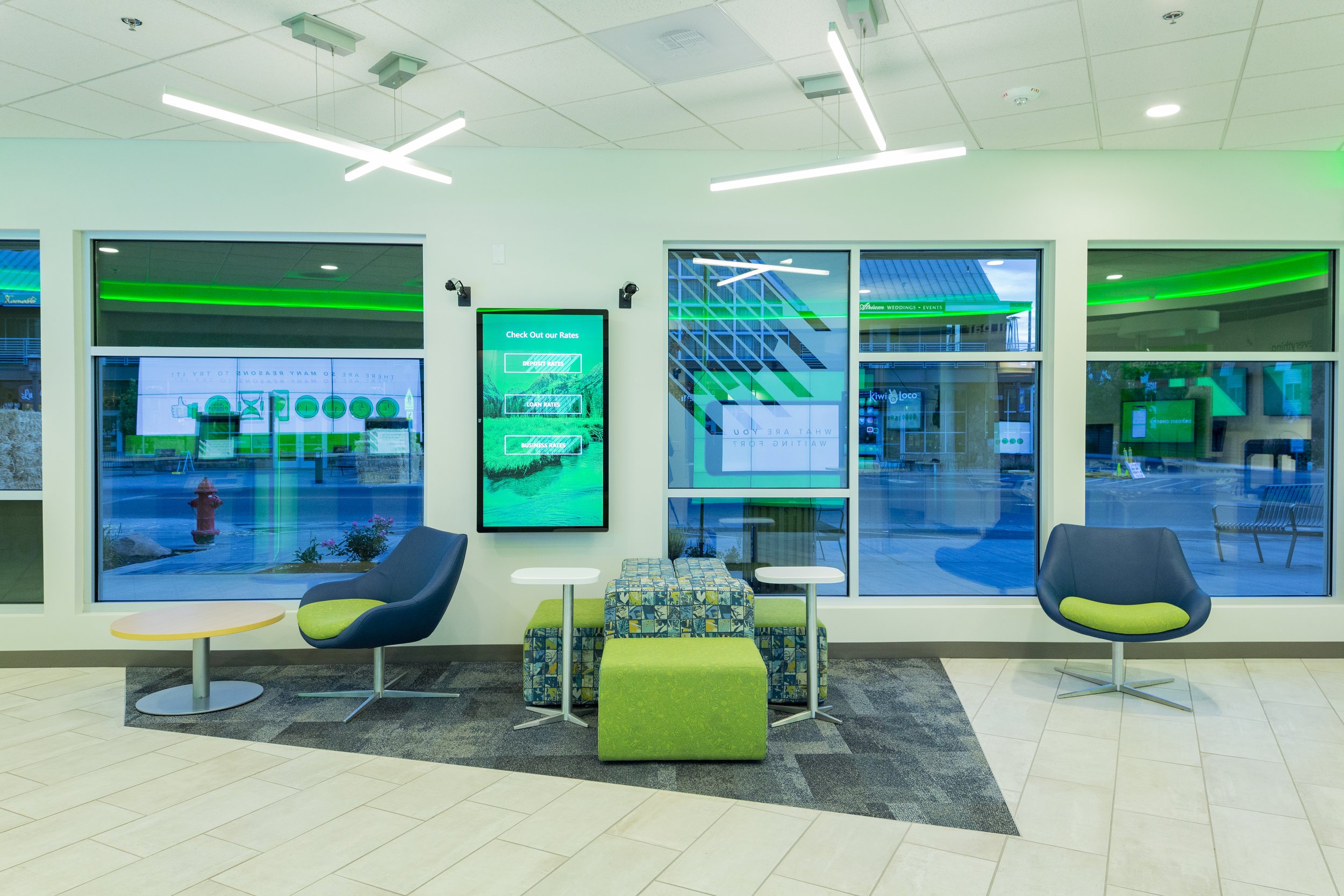 A waiting room with green and blue sofas and chairs.