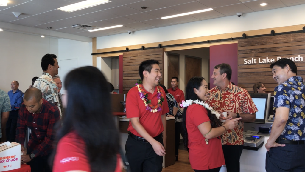 A group of employees in Hawaiian shirts, all laughing.