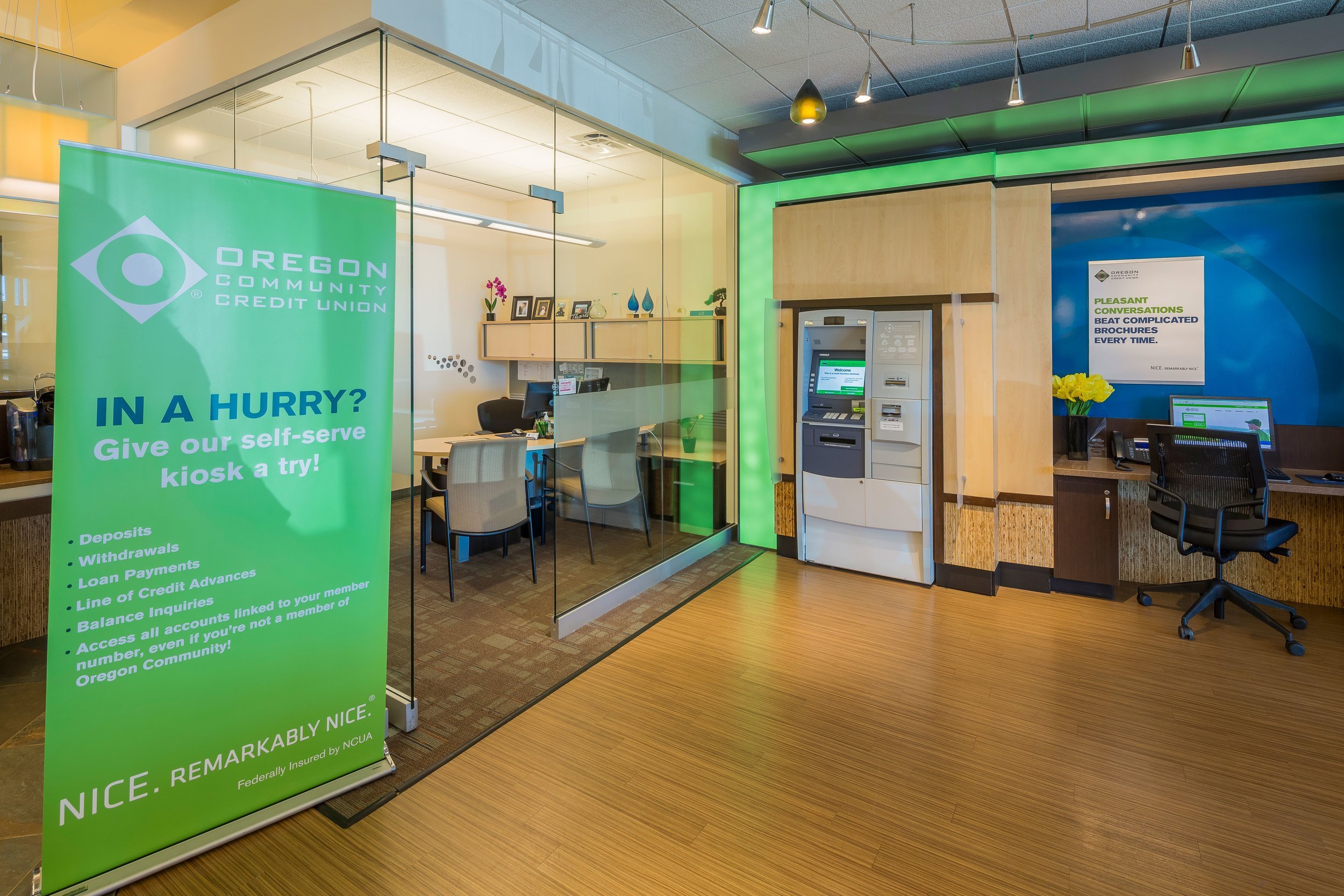 A bank lobby with a glass office and a self-serve teller machine.
