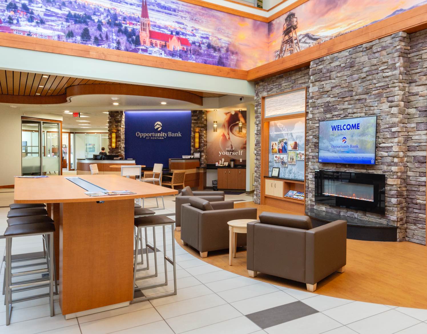 A large bank lobby with a waiting area, fireplace, large table, and chairs.