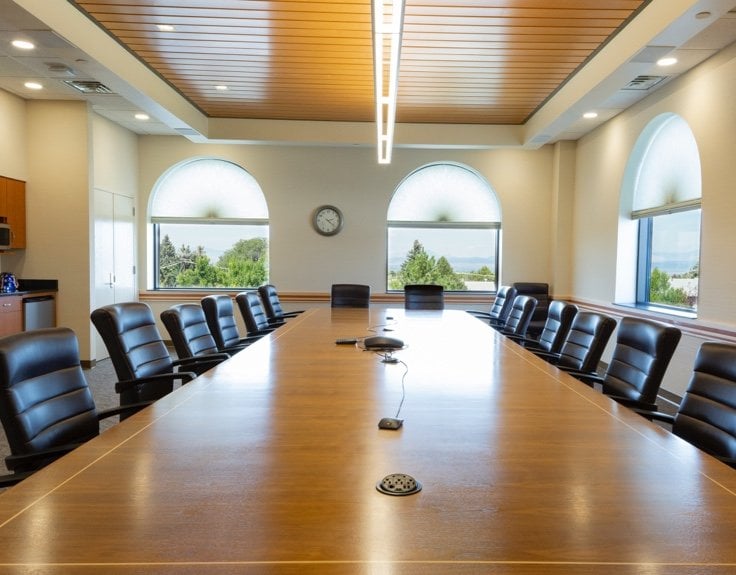 A conference room with a large table surrounded by office chairs.