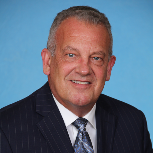 An older man in a black suit and blue tie.