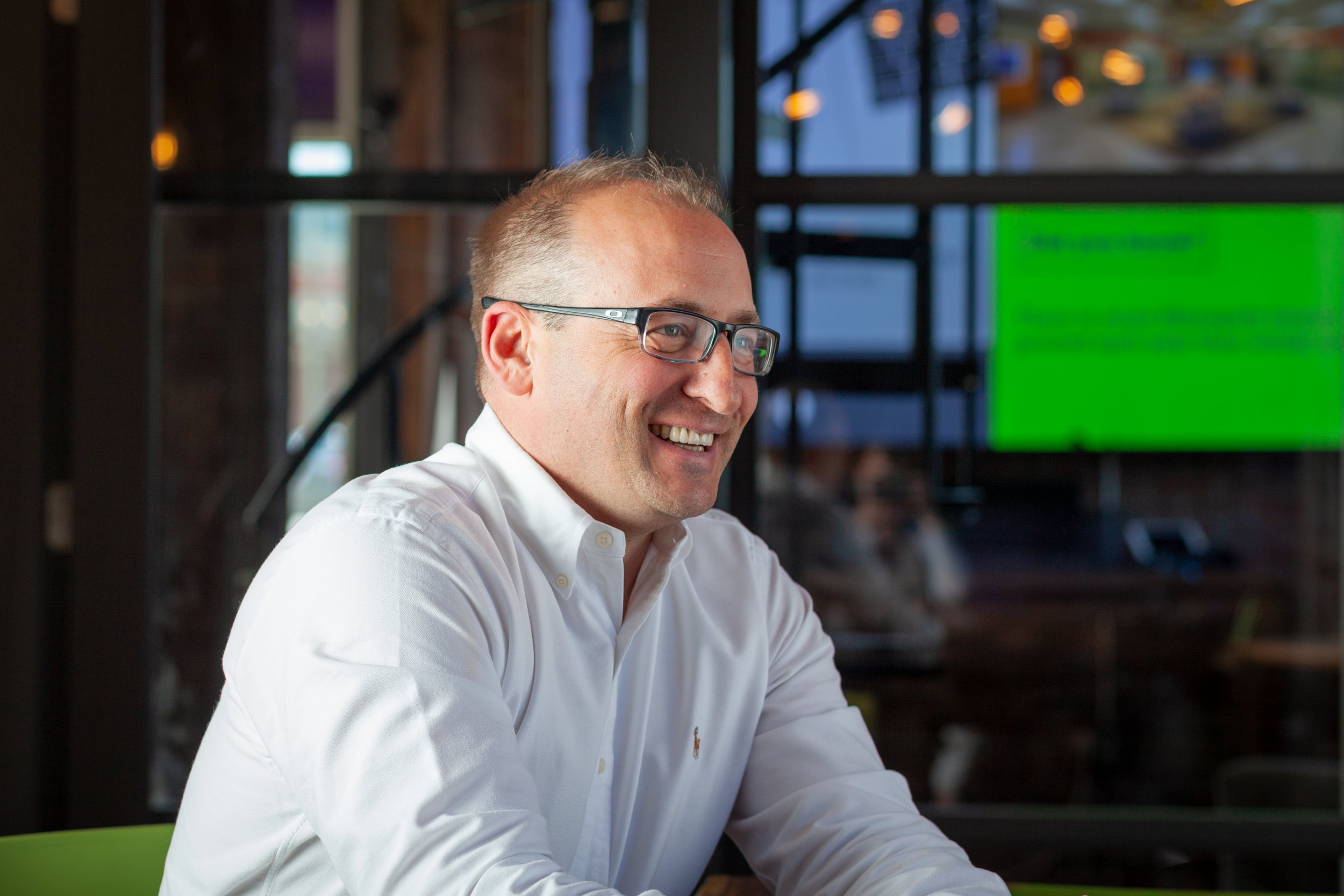 A man laughing, in a white button-up.