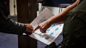Two people holing and pointing at blueprints.