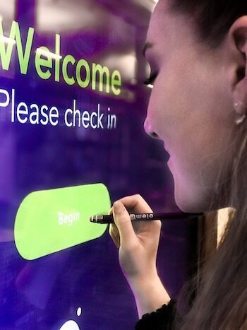 A woman using a touch screen with a pen stylus.