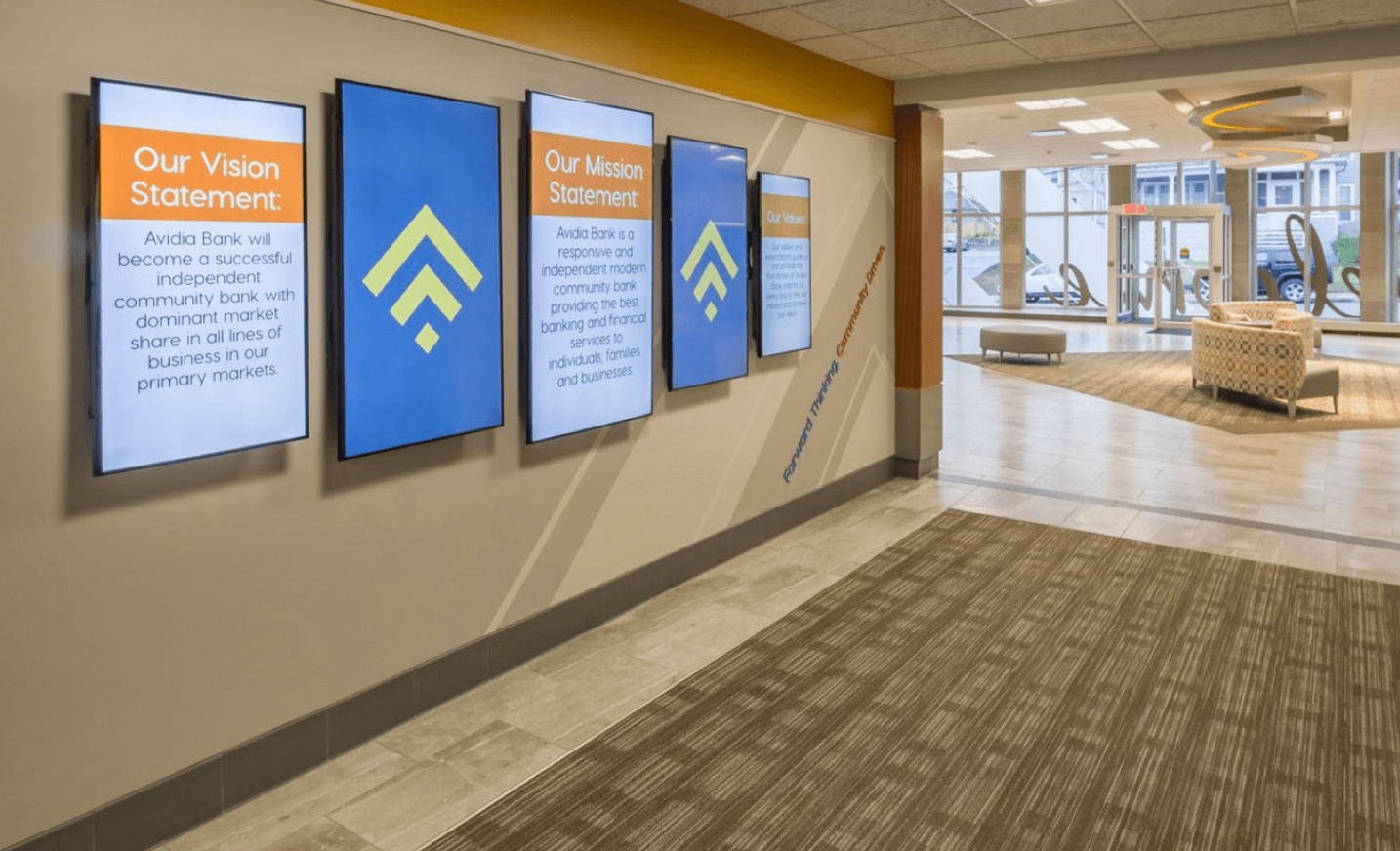 A bank lobby with digital signage solutions displaying the institution's vision and mission statements on mounted screens.