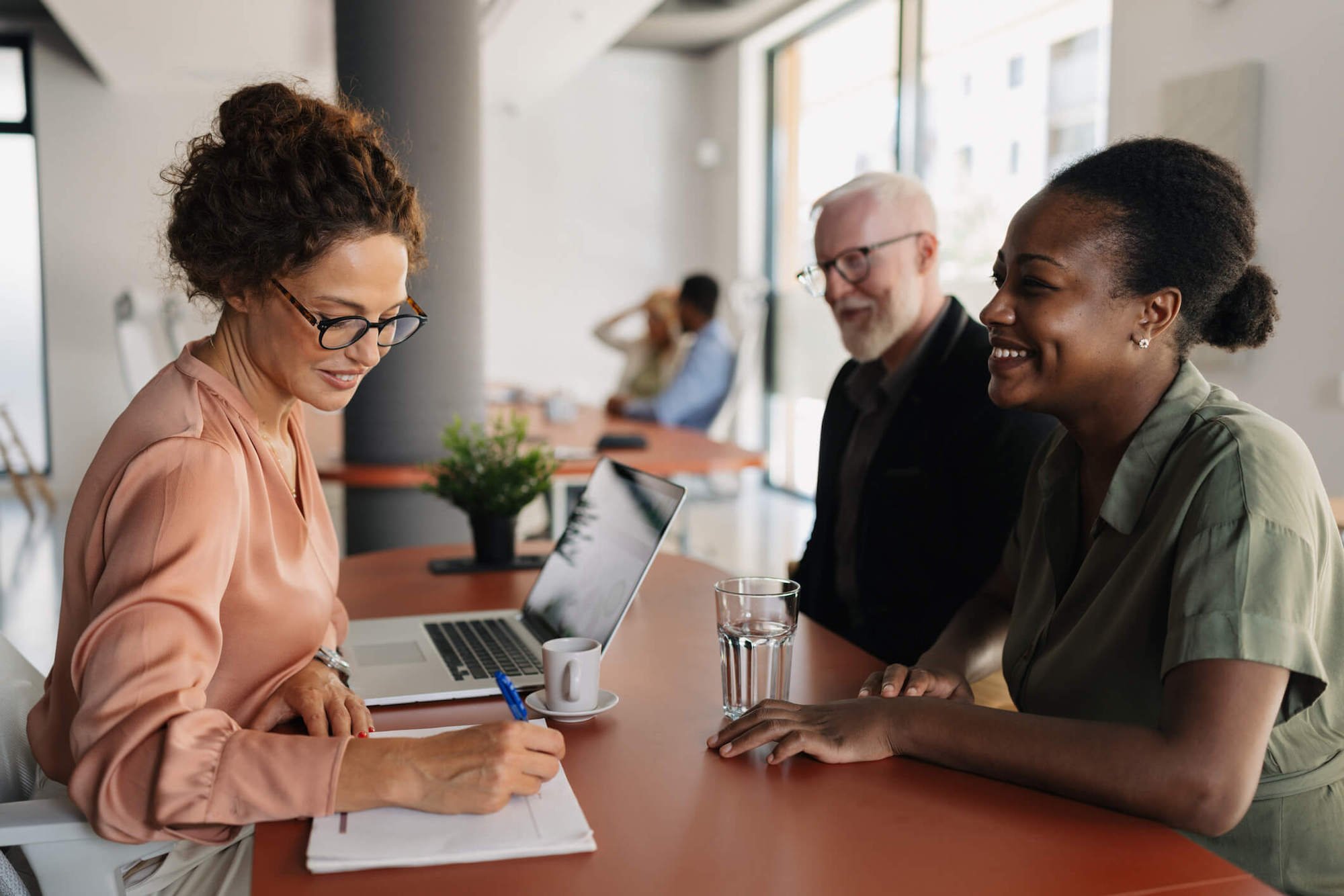 a female bank teller talking to a man and woman