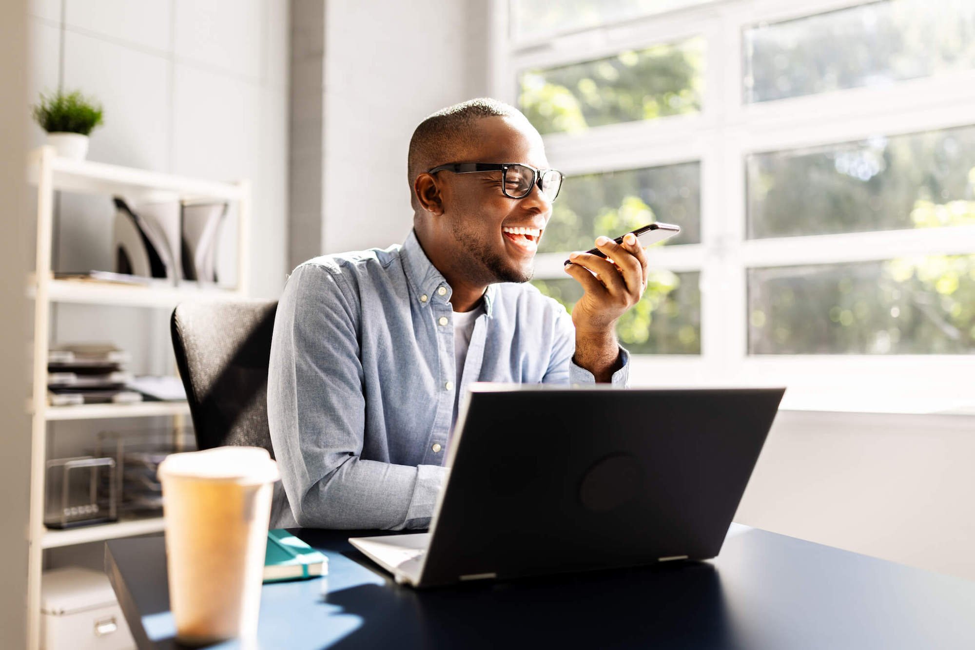 man sitting at his desk talking on the phone and smiling
