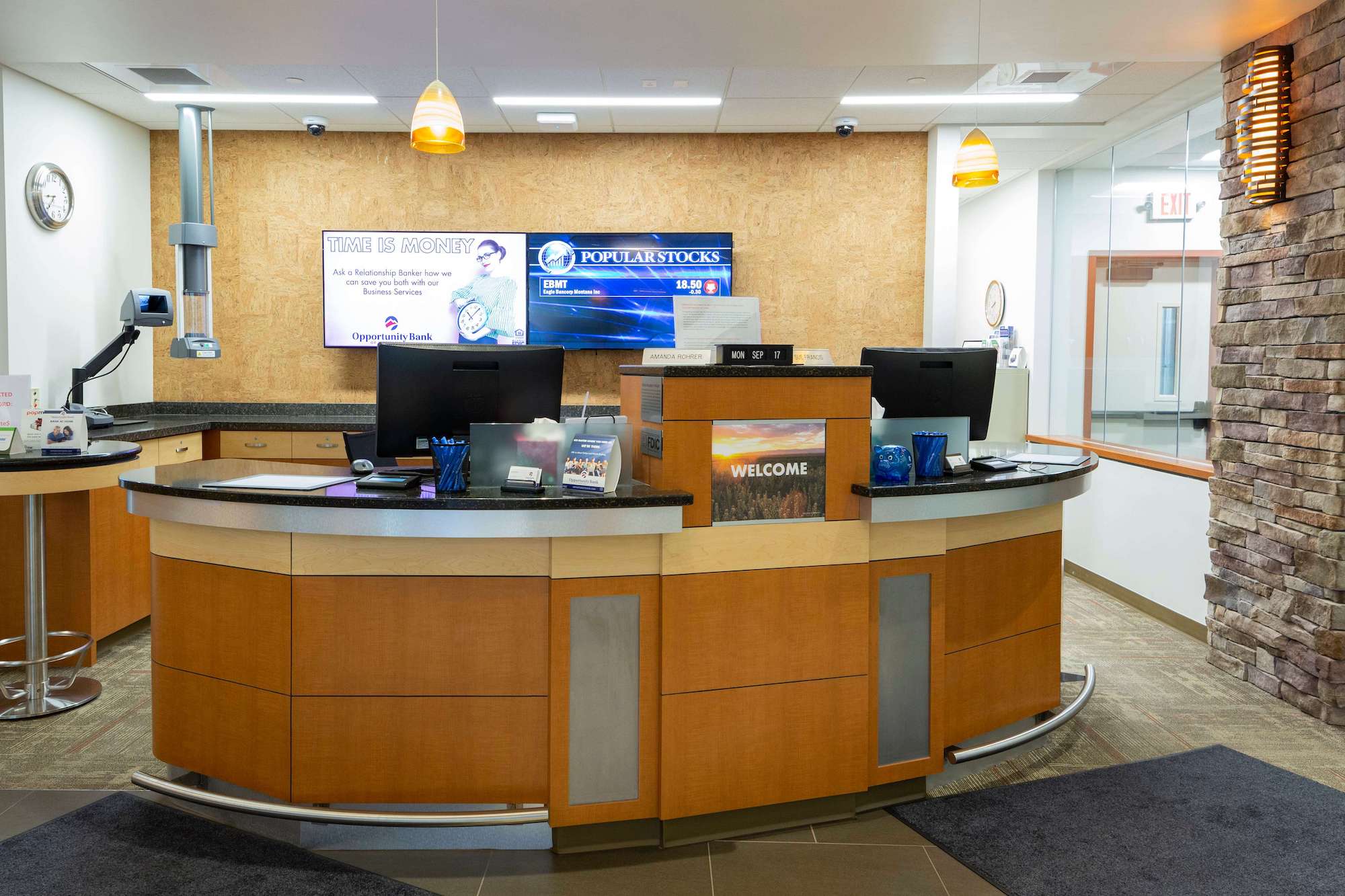 bank teller desk in front of a wooden wall with monitors on it