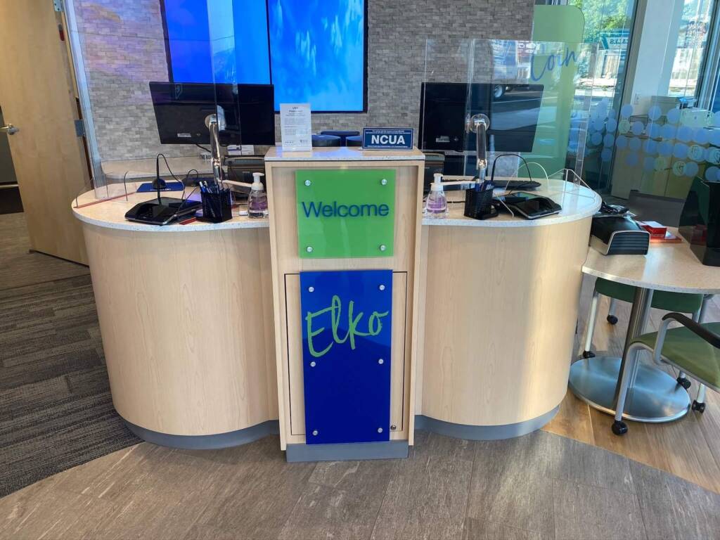 2 computers sitting on top of a counter at a bank